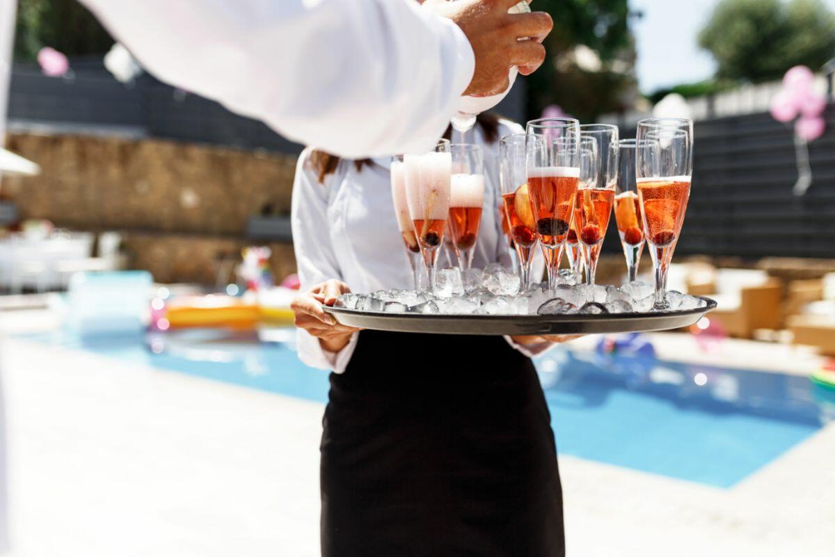 privékok serveert champagne aan het zwembad van een luxe villa op Ibiza
