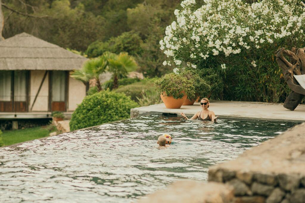 Zwembad en mediterrane tuin bij Villa Paradiso op Ibiza, met gasten die van het water genieten.
