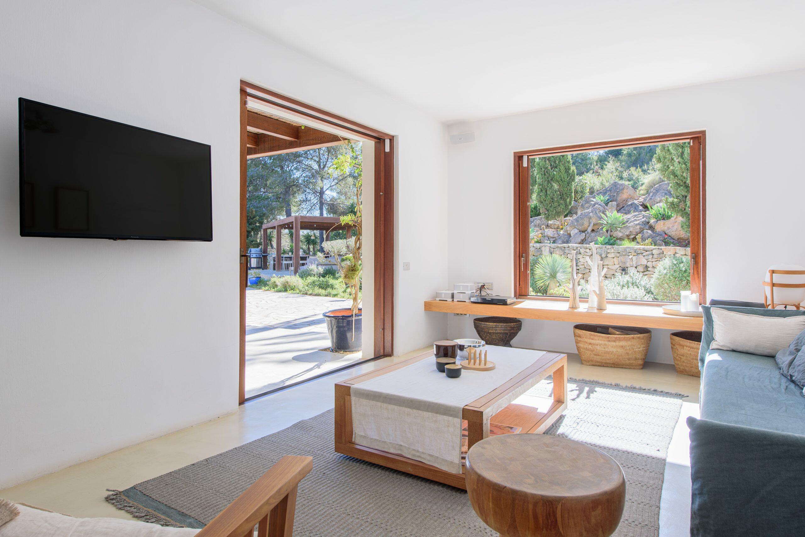Lichte woonkamer in een huis op Ibiza met grote openingen naar de tuin en natuurlijk licht.